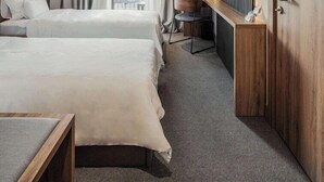A hotel room with two beds, a desk, a chair, a TV, and a large wardrobe.