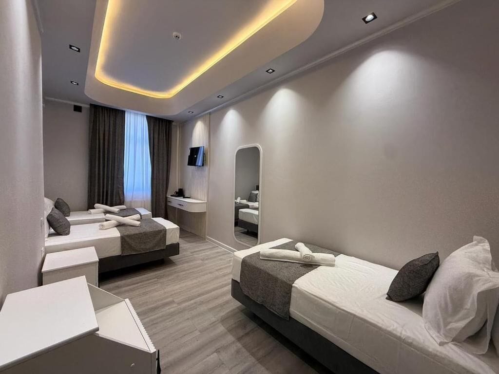 Una habitación de hotel moderna con dos camas, un escritorio, un espejo y un televisor.