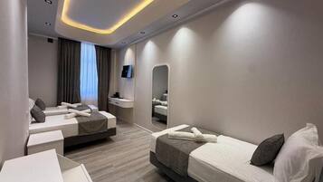 Una habitación de hotel moderna con dos camas, un escritorio, un espejo y un televisor.