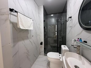 A modern bathroom with a toilet, sink, and glass shower enclosure. - Turkezm Hotel (Urgench)