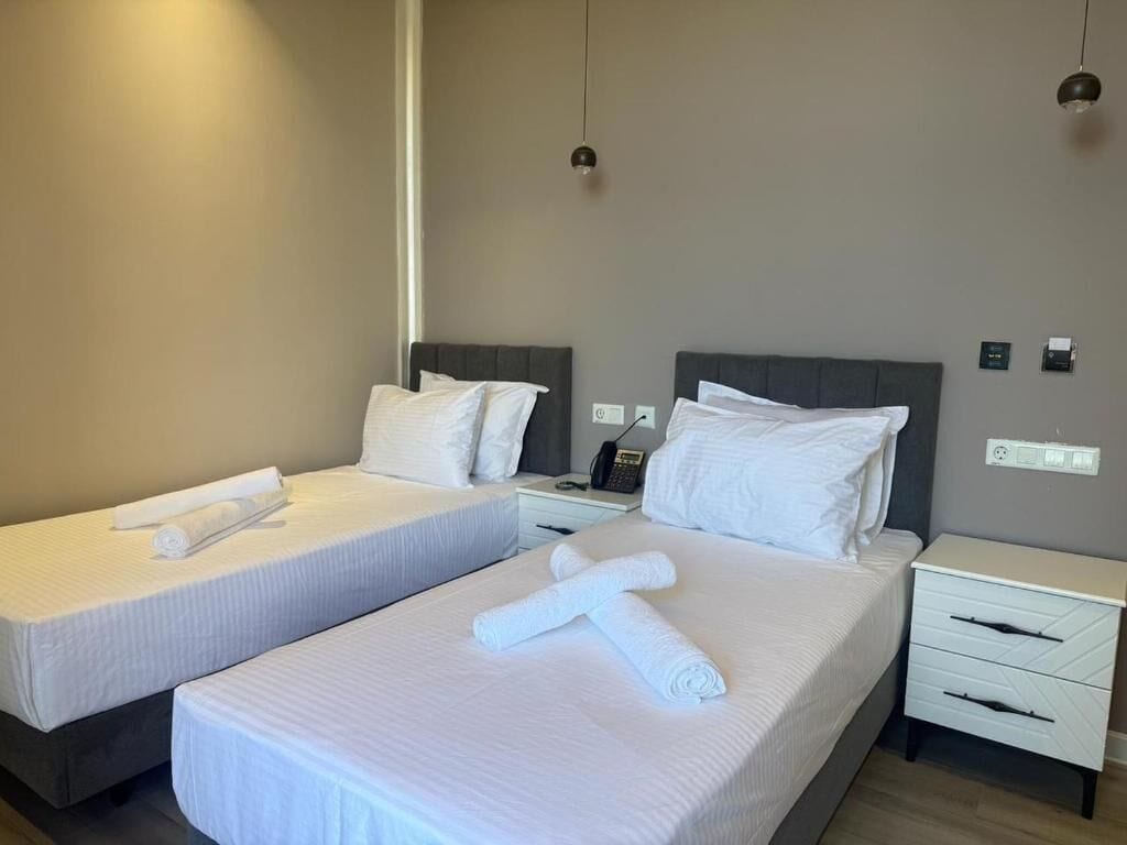 Una camera d'albergo con due letti, lenzuola bianche, comodini e un telefono fissato alla parete.