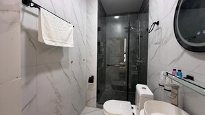 Un baño moderno con cabina de ducha de vidrio, inodoro y lavamanos.