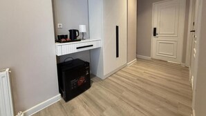 Una habitación con un armario blanco, una bolsa negra, una tetera y una cafetera sobre un estante blanco.