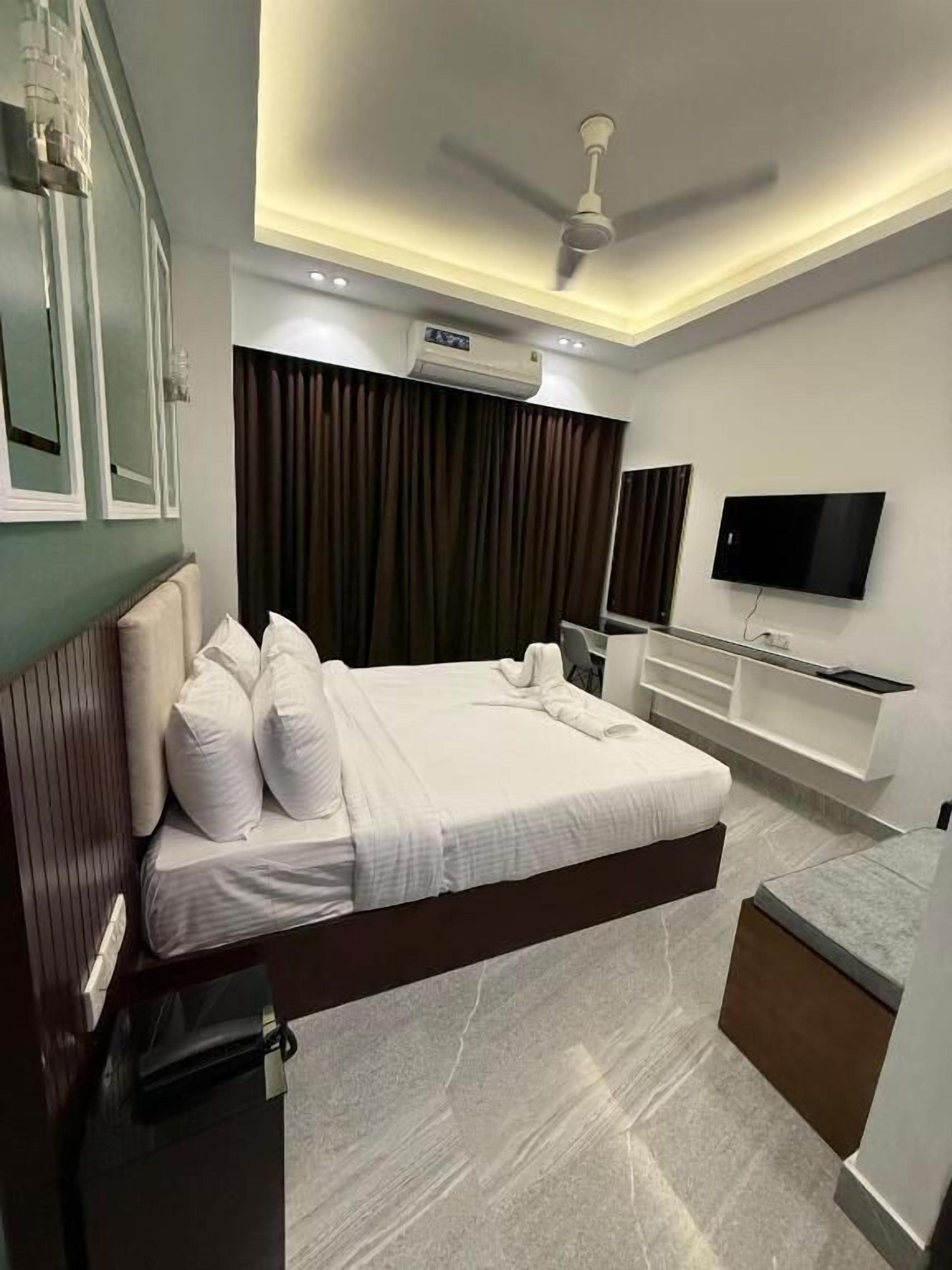 A modern hotel room with a bed, a TV, a ceiling fan, and a built-in air conditioning unit.