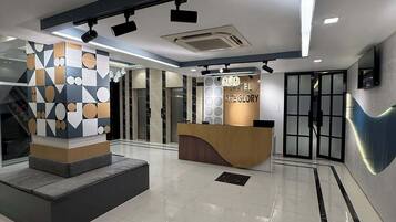 A modern hotel lobby with a reception desk, a geometric art installation, and a clean, tiled floor.