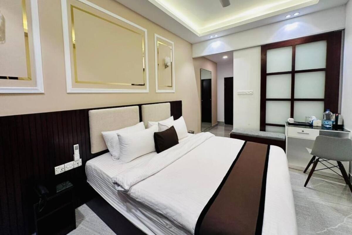 A modern hotel room with a large bed, a desk, and a ceiling fan.