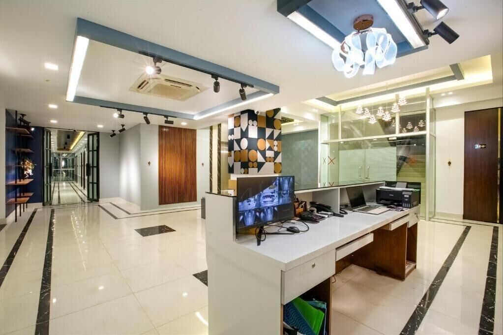 A modern office space with a reception desk, a television, and a glass partition.