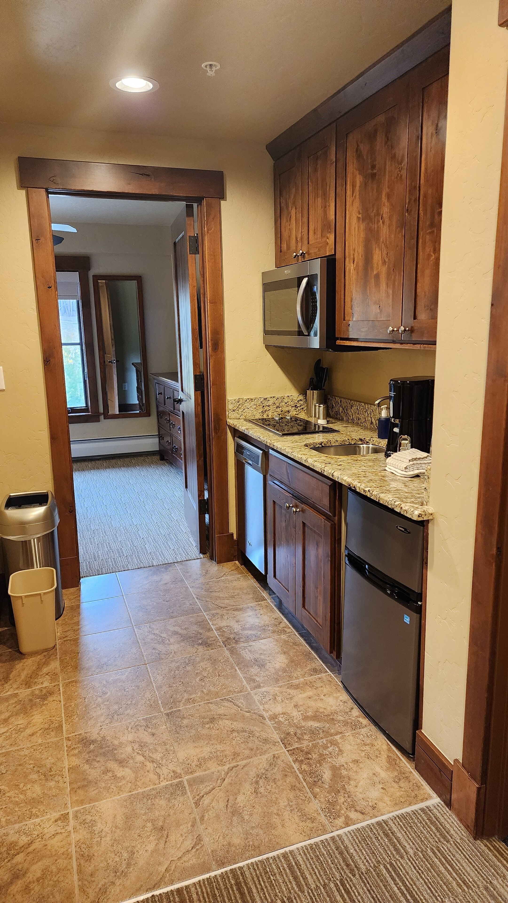 A kitchen with wooden cabinets, a stainless steel microwave, a coffee maker, and a dishwasher.