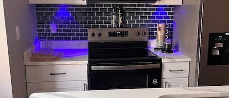 A modern kitchen with white cabinets, a black microwave, a stainless steel sink, and a coffee maker.