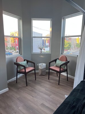 A room with two chairs, a small table, and a window with a view of buildings.
