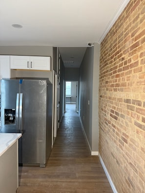 A kitchen with a stainless steel refrigerator, white cabinets, and a wooden floor.