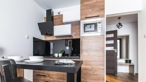 Una cucina compatta con forno a microonde, una sedia nera e un tavolo da pranzo.