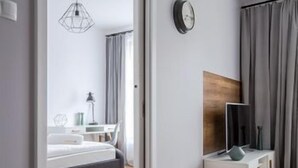 Una camera da letto moderna con un letto, un comodino, una lampada e una TV su un mobile bianco.