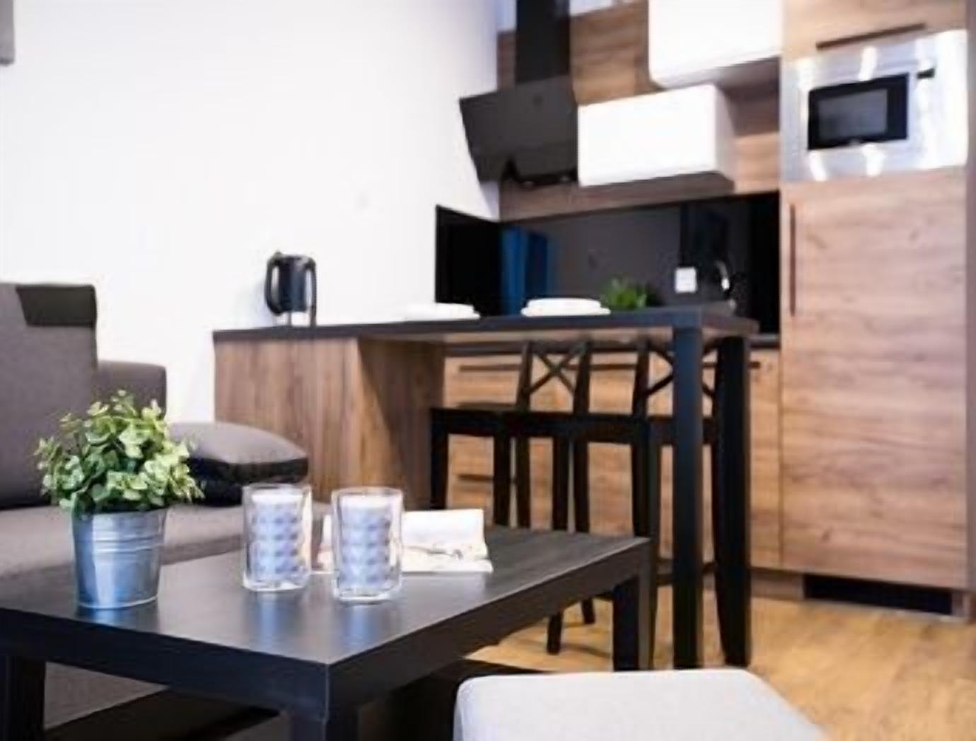 A modern kitchen with wooden cabinets, a dining table, and a sofa.