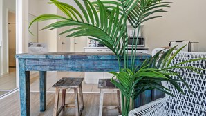A dining area with a blue-painted table, two stools, and a white wicker chair. - Comfy Studio Apartment in Marcoola Beach (Sunshine Coast)