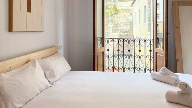 Ein Hotelzimmer mit Bett, einer Hängelampe, Blick auf die Straße und einer Tür nach draußen.