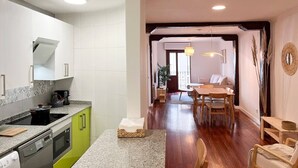 Eine moderne Küche mit Backofen, ein Essbereich mit Holzmöbeln und ein großes Fenster für natürliches Licht.