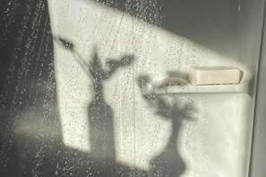 A bathroom with a shower, a soap bar, and a window with condensation. - Ko Lanta Hotels and Working Space (Koh Lanta)