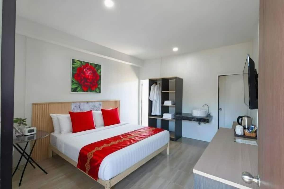 A modern hotel room with a bed, a desk, a wardrobe, and a television.