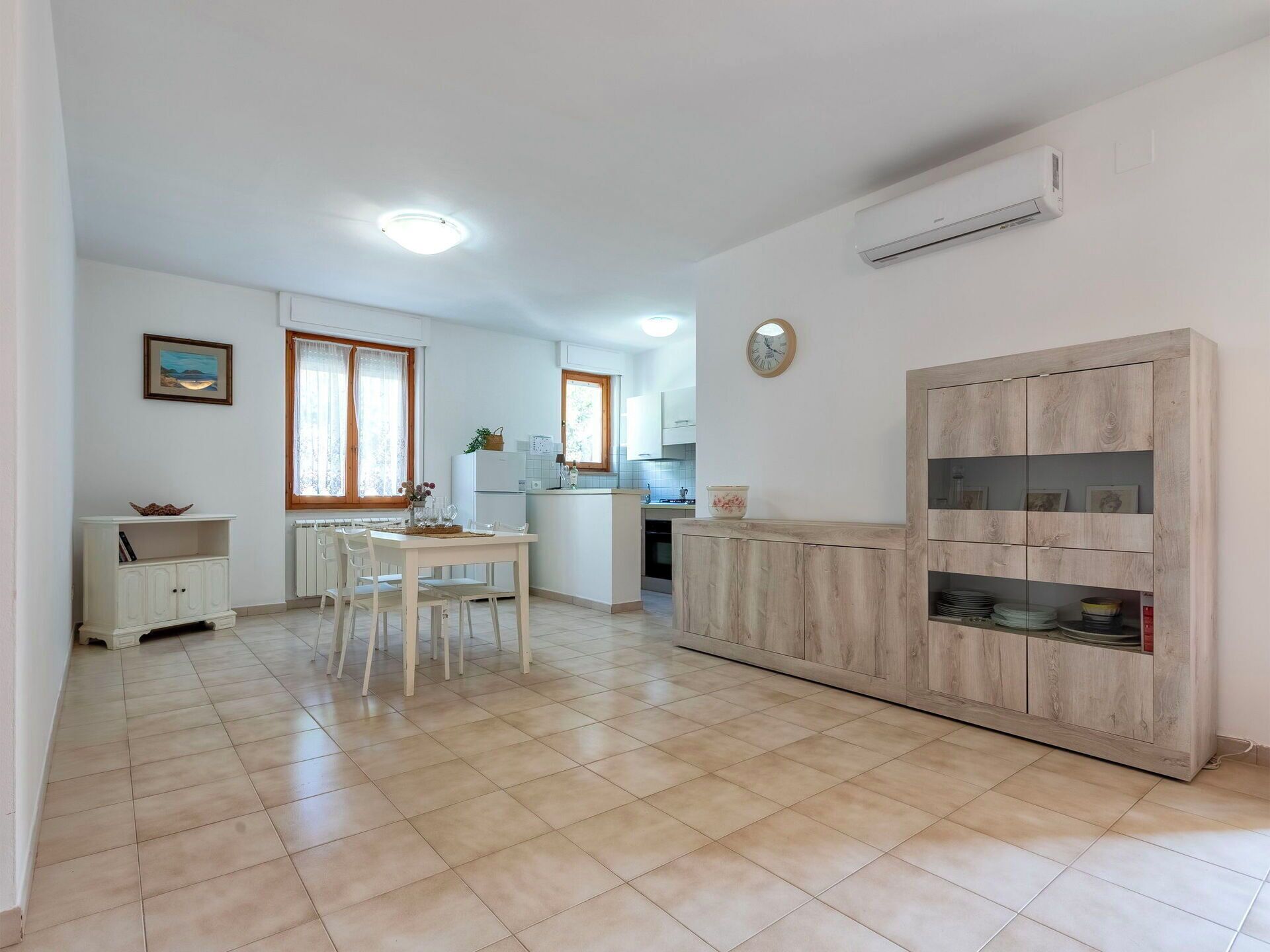 Cozinha ampla com área de jantar, armário de madeira com prateleiras e um relógio na parede.
