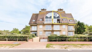 Un edificio residenziale a più piani con una finestra ad arco centrale, numerosi balconi e facciata in mattoni.