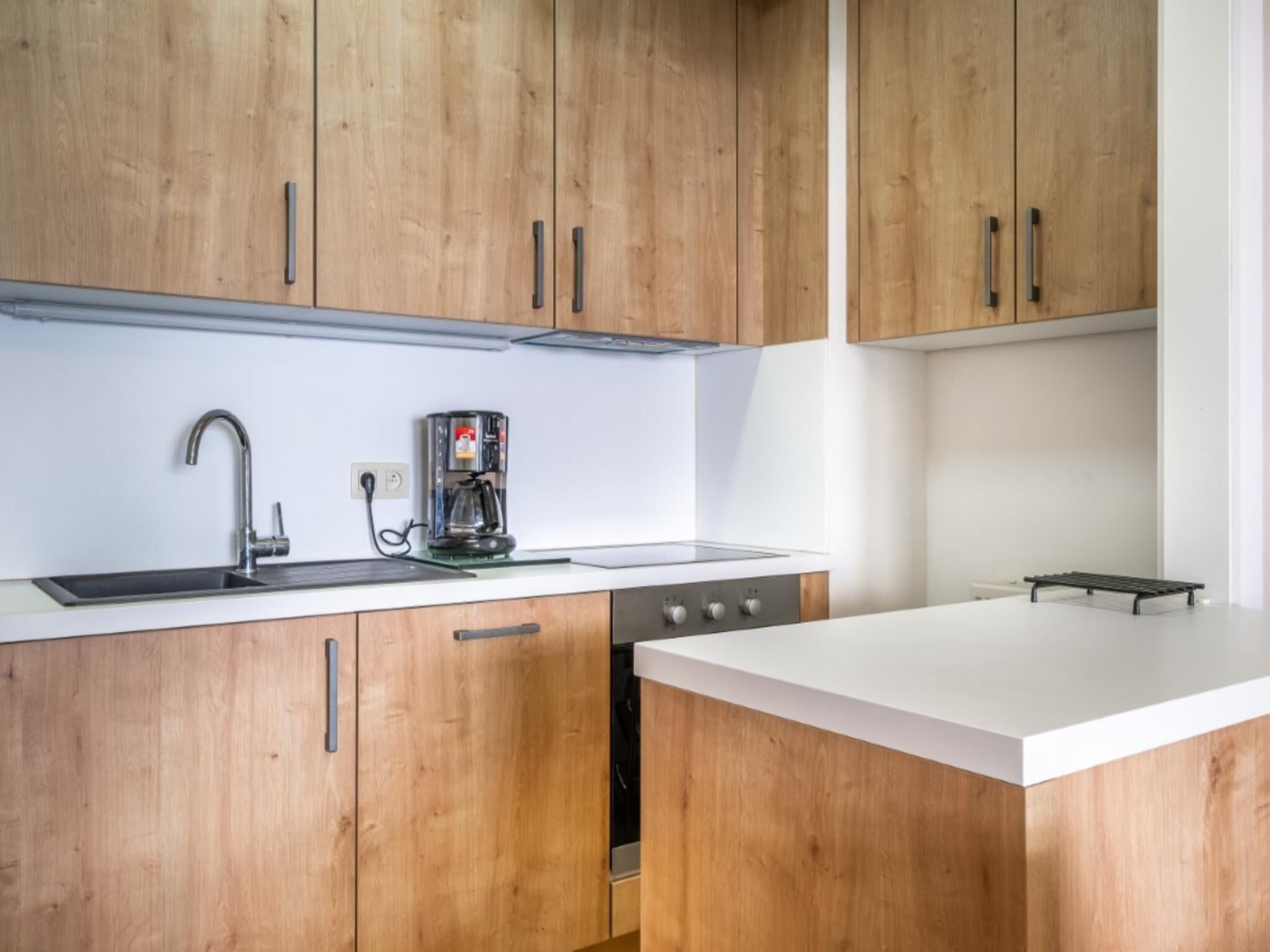 Een moderne keuken met houten kastjes, een roestvrijstalen spoelbak, een koffiezetapparaat en een fornuis.