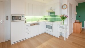 Une cuisine moderne avec des meubles blancs, un four à micro-ondes, un évier et une cuisinière.