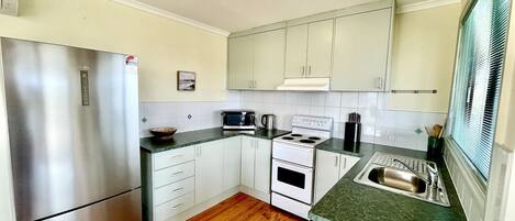 A compact kitchen with a stainless steel refrigerator, a microwave, a stove, and a sink.
