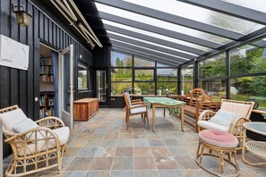 A covered patio with wicker furniture, a table, and a bookshelf. - Lovely holiday home near Hornbæk (Hornbæk)