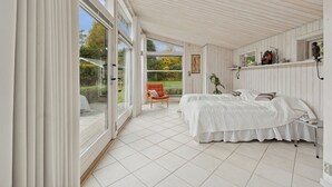 Un dormitorio con una cama, una silla, una mesita de noche y una ventana.