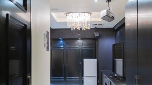 A modern kitchen with a chandelier, recessed lighting, and dark cabinetry. - Hotel Rima chocolat (Sapporo)