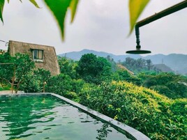 Uma piscina com vista para uma cordilheira, rodeada por vegetação exuberante.