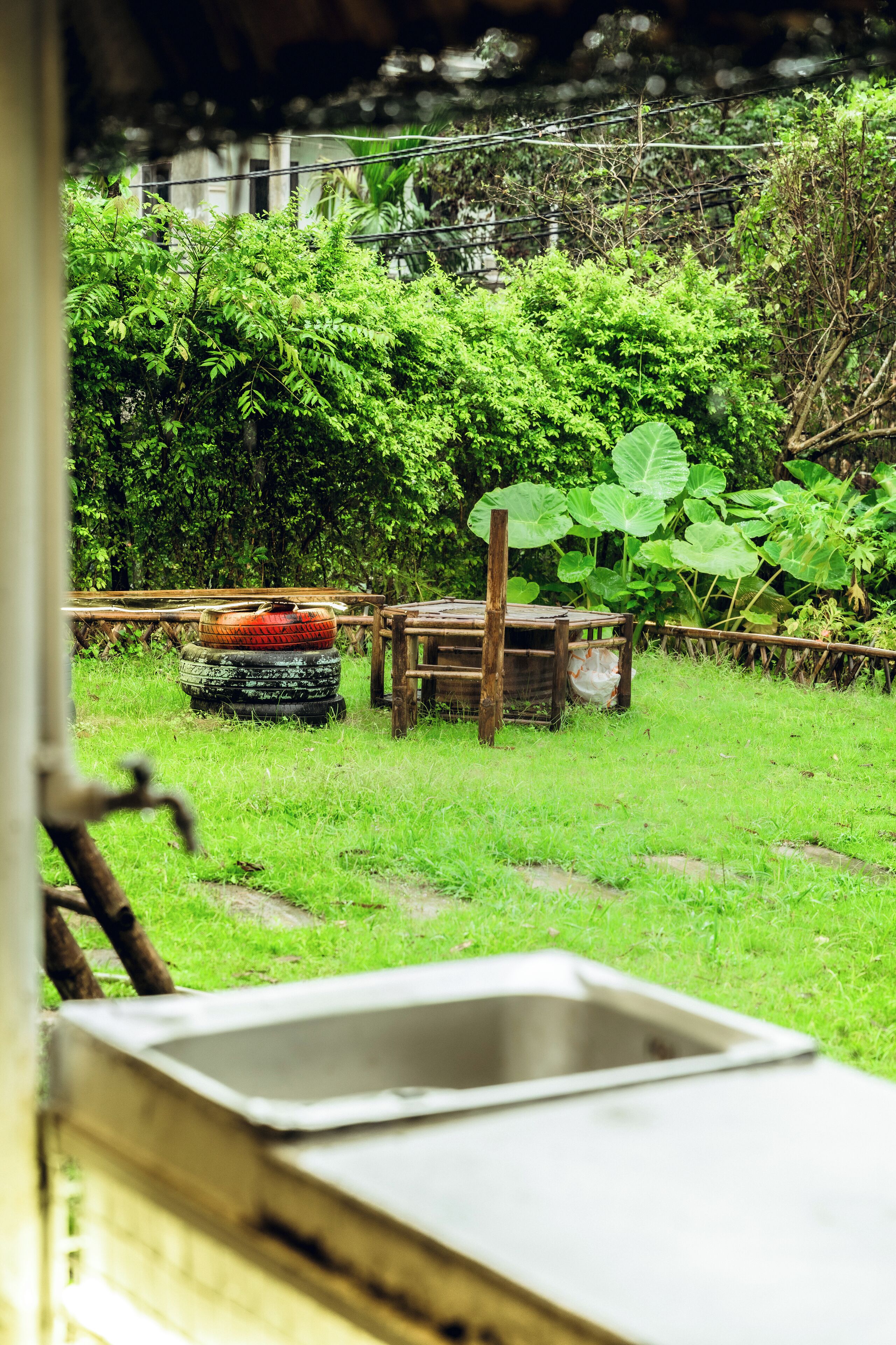 A rustic outdoor area with a wooden bench, a metal sink, and a pile of tires.