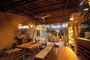 Un interior rústico con bancos de madera, una mesa larga y lámparas colgantes.