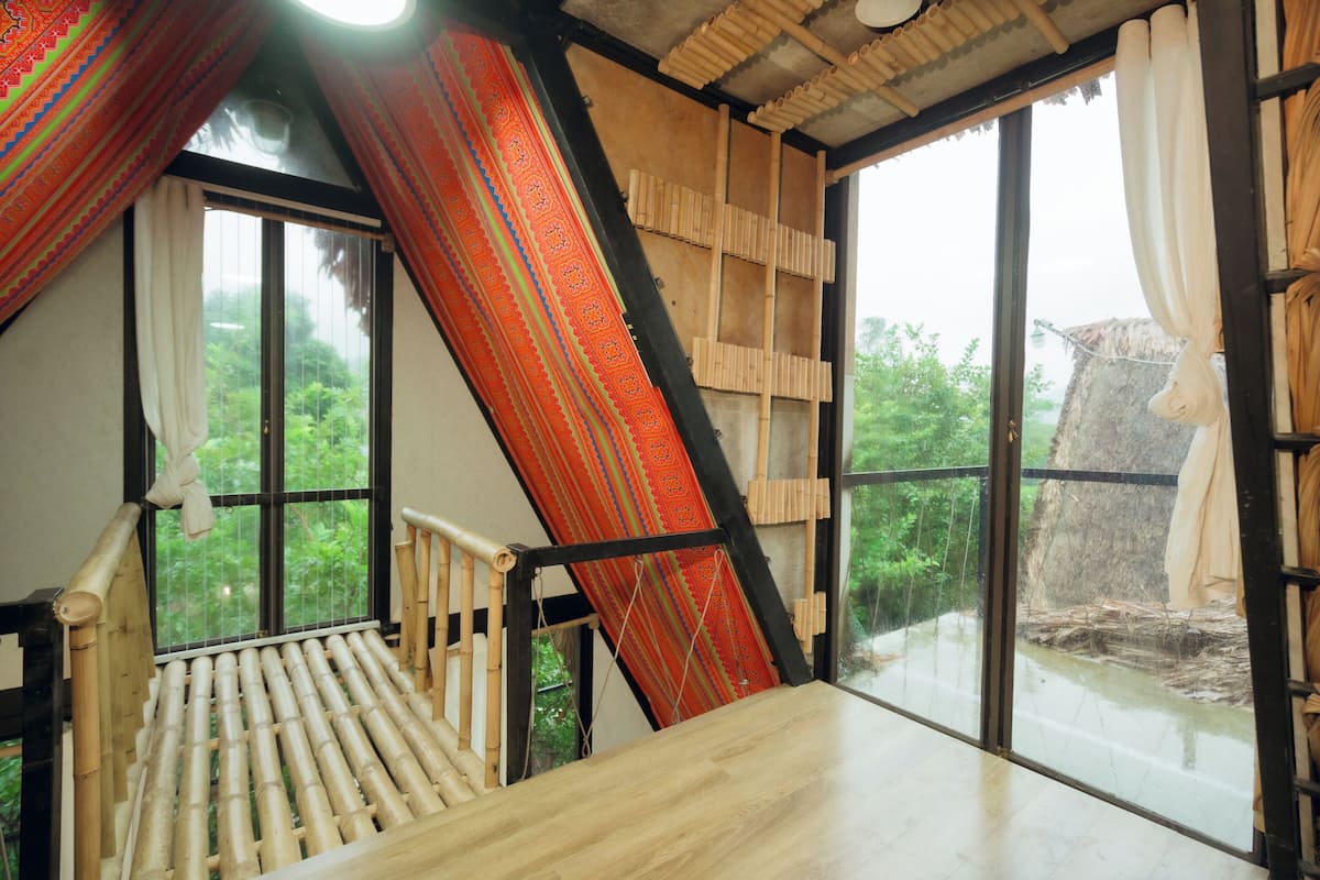 Una habitación con una cama de madera, ventanas amplias y vista a espacios verdes.