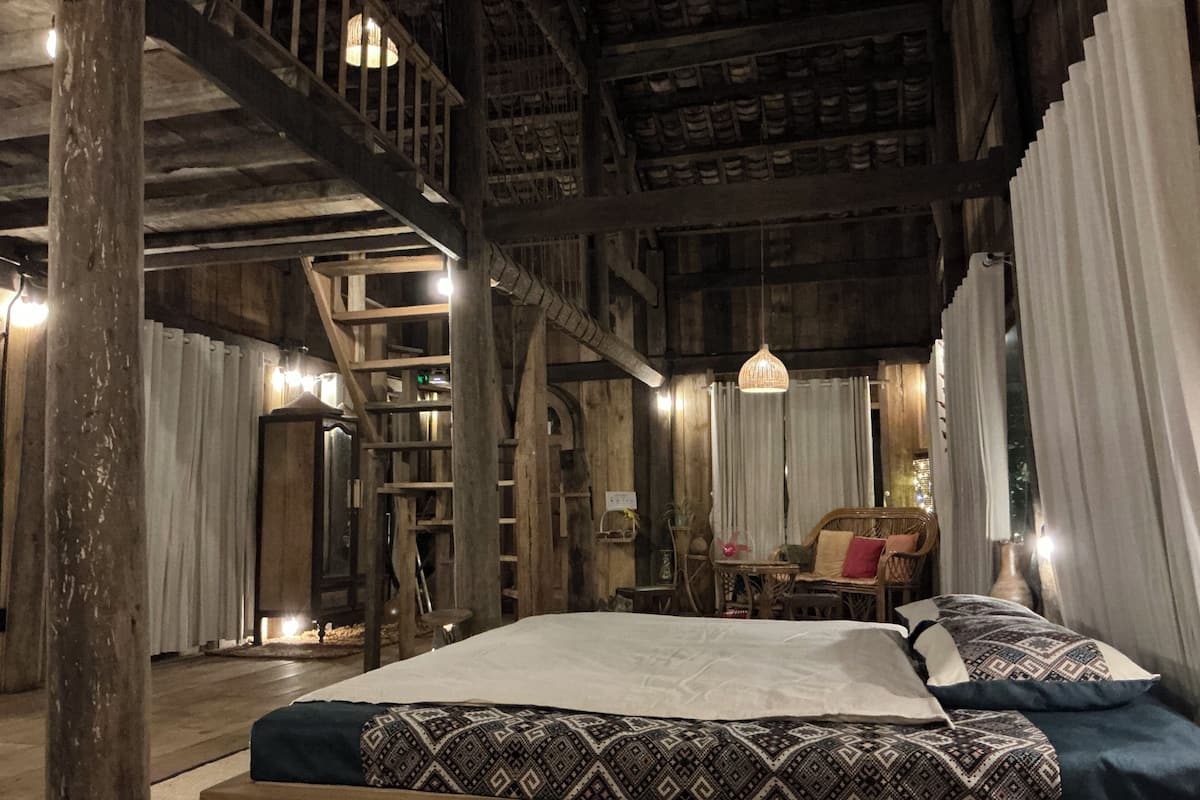 Una habitación rústica de madera con una cama, una silla, una mesa y una escalera.