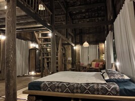 Um quarto rústico de madeira com uma cama, uma cadeira, uma mesa e um lance de escadas.