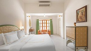 A hotel room with a large bed, a sofa, a small table, and a decorative cabinet. - Gaj Kesri by 7Apple Resorts  (Bikaner)