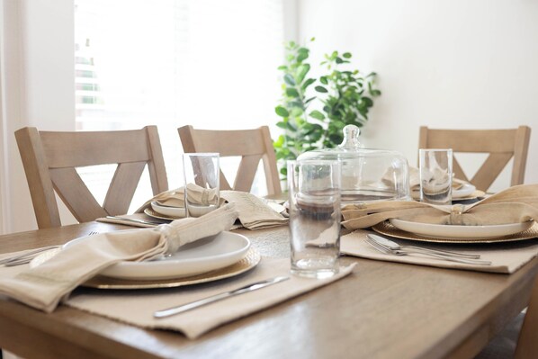A dining table set with plates, glasses, and cutlery, with a water bottle and a glass jar on the table.