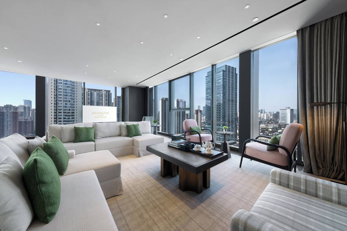 A modern living room with a sofa, armchairs, a coffee table, and a city view.