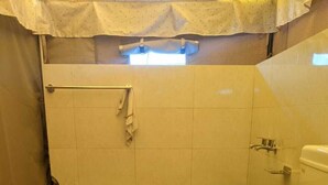 Une petite salle de bain avec des toilettes, un rideau de douche et un porte-serviettes.