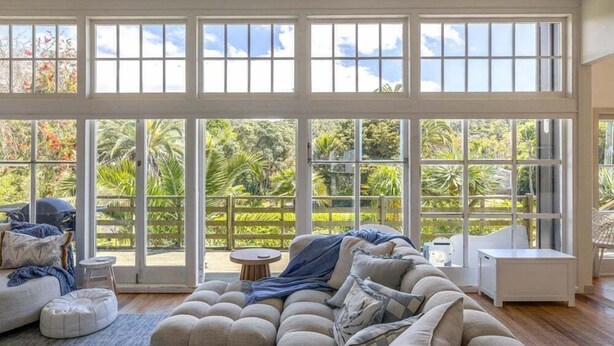 Un salón amplio con un gran ventanal que da a un jardín exuberante.