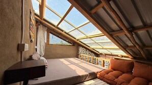 A cozy attic bedroom with a skylight, a bed, a sofa, and a small desk. - KALA STUDIO AND STAY (Kullu)