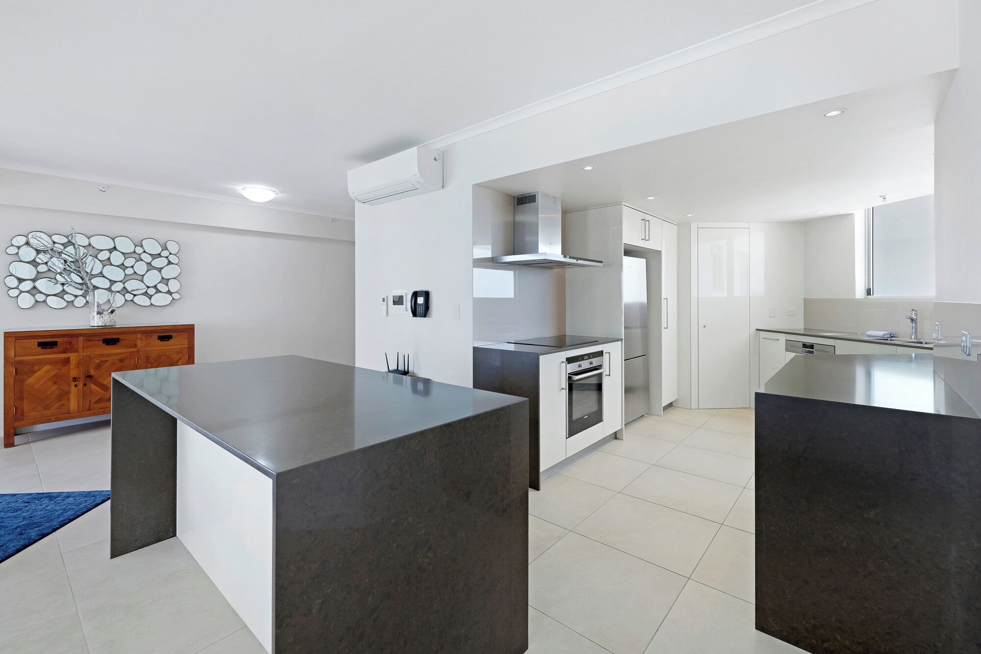 A modern kitchen with dark countertops, stainless steel appliances, and a wooden cabinet.
