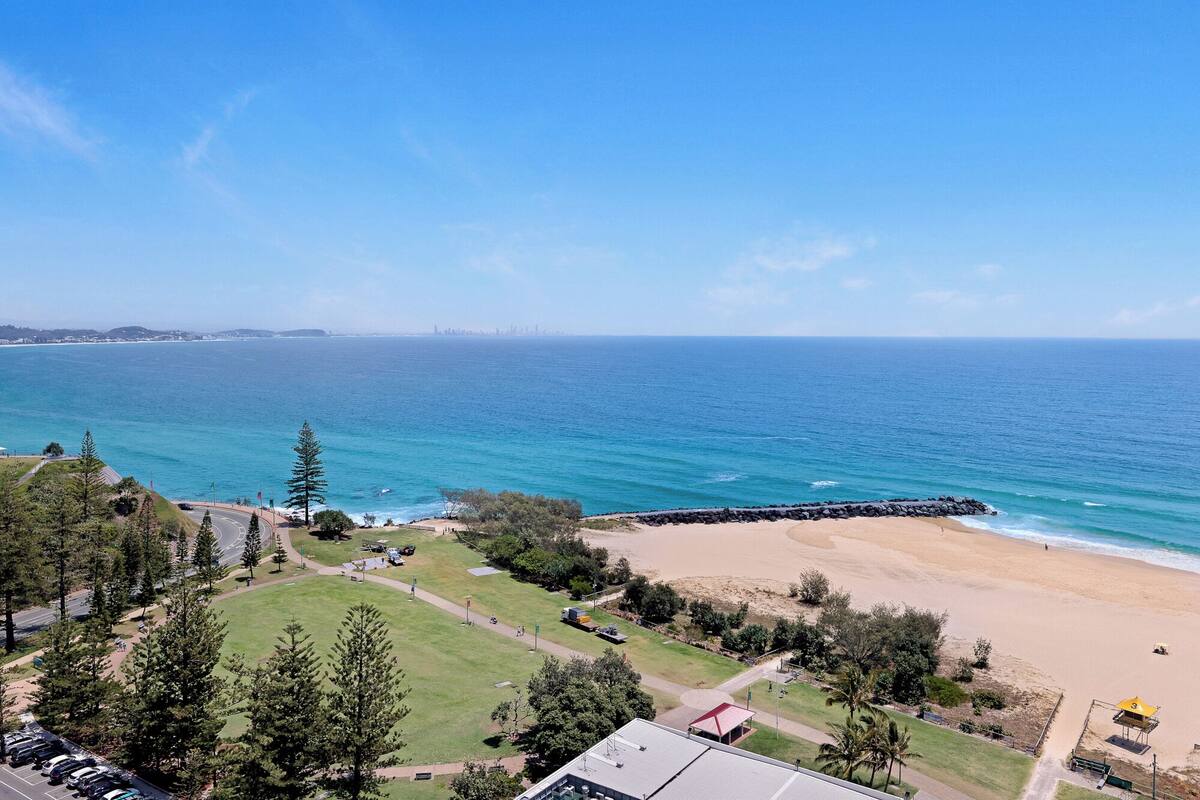 Une vue sur la côte, avec une plage, un espace de stationnement et une route menant à la plage.