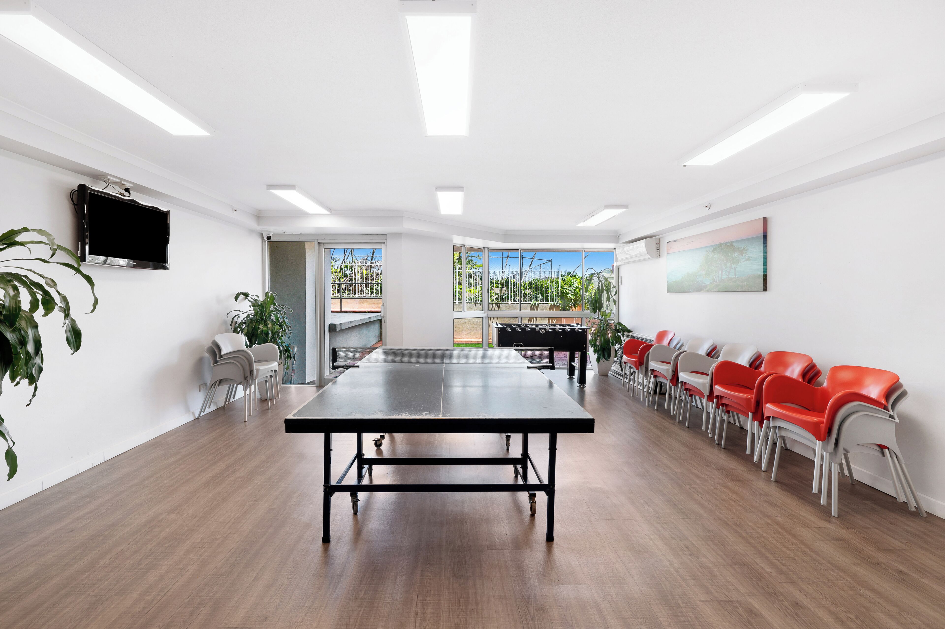 A spacious room with a ping pong table, seating, and a large window with a view.