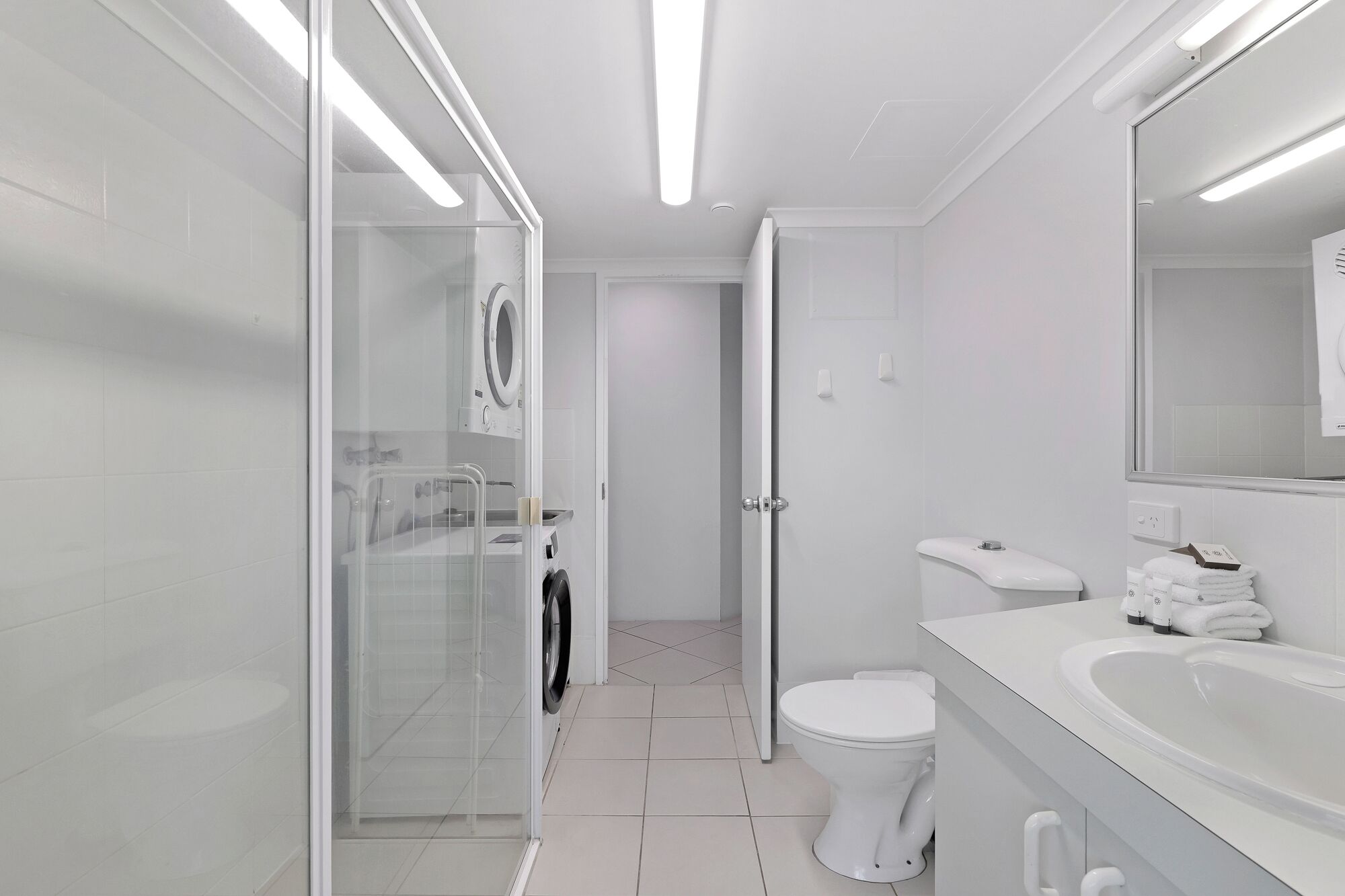 Ein modernes Badezimmer mit Duschkabine aus Glas, Toilette und Waschbecken mit Spiegel.