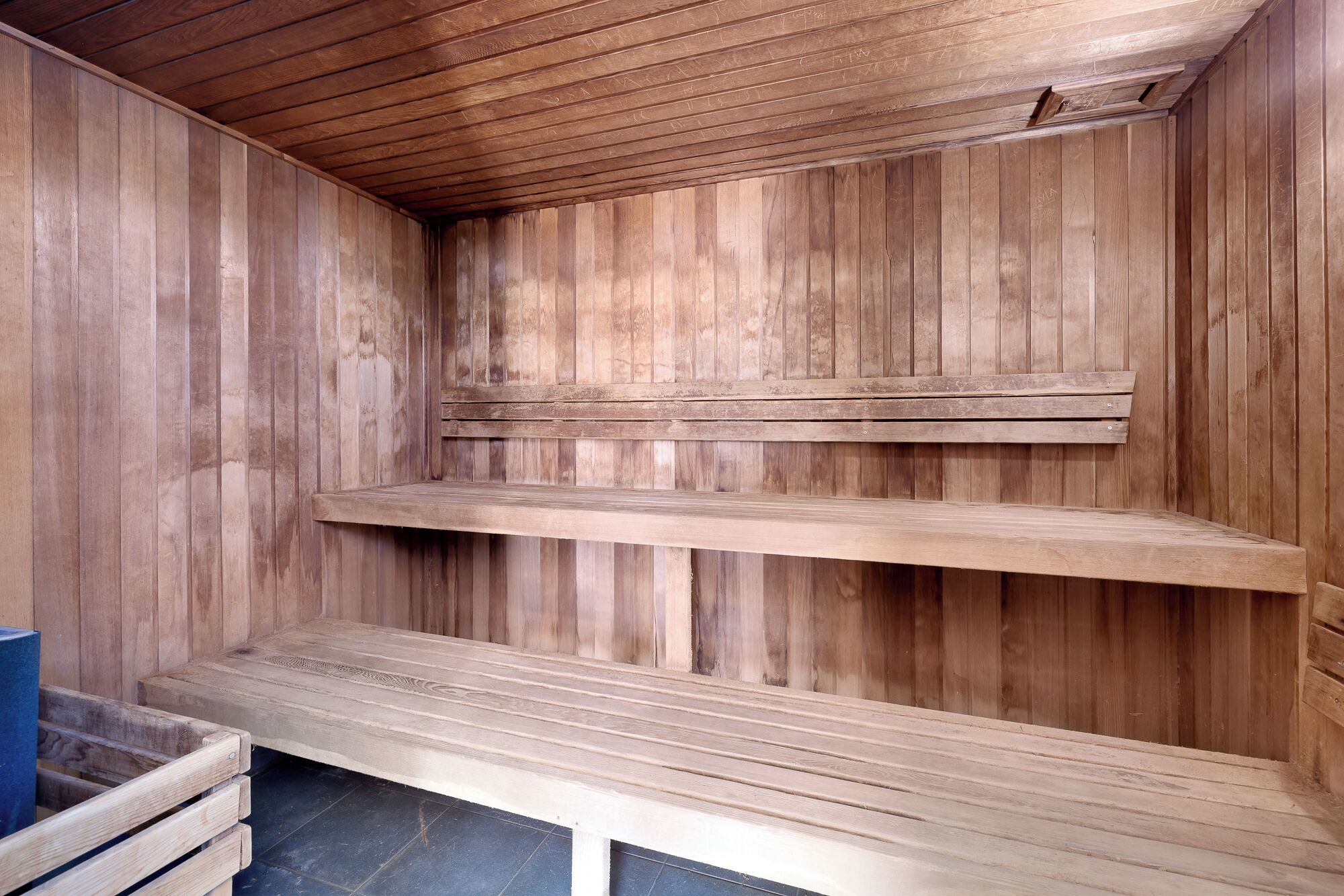 A wooden interior with three wooden shelves and a bench.