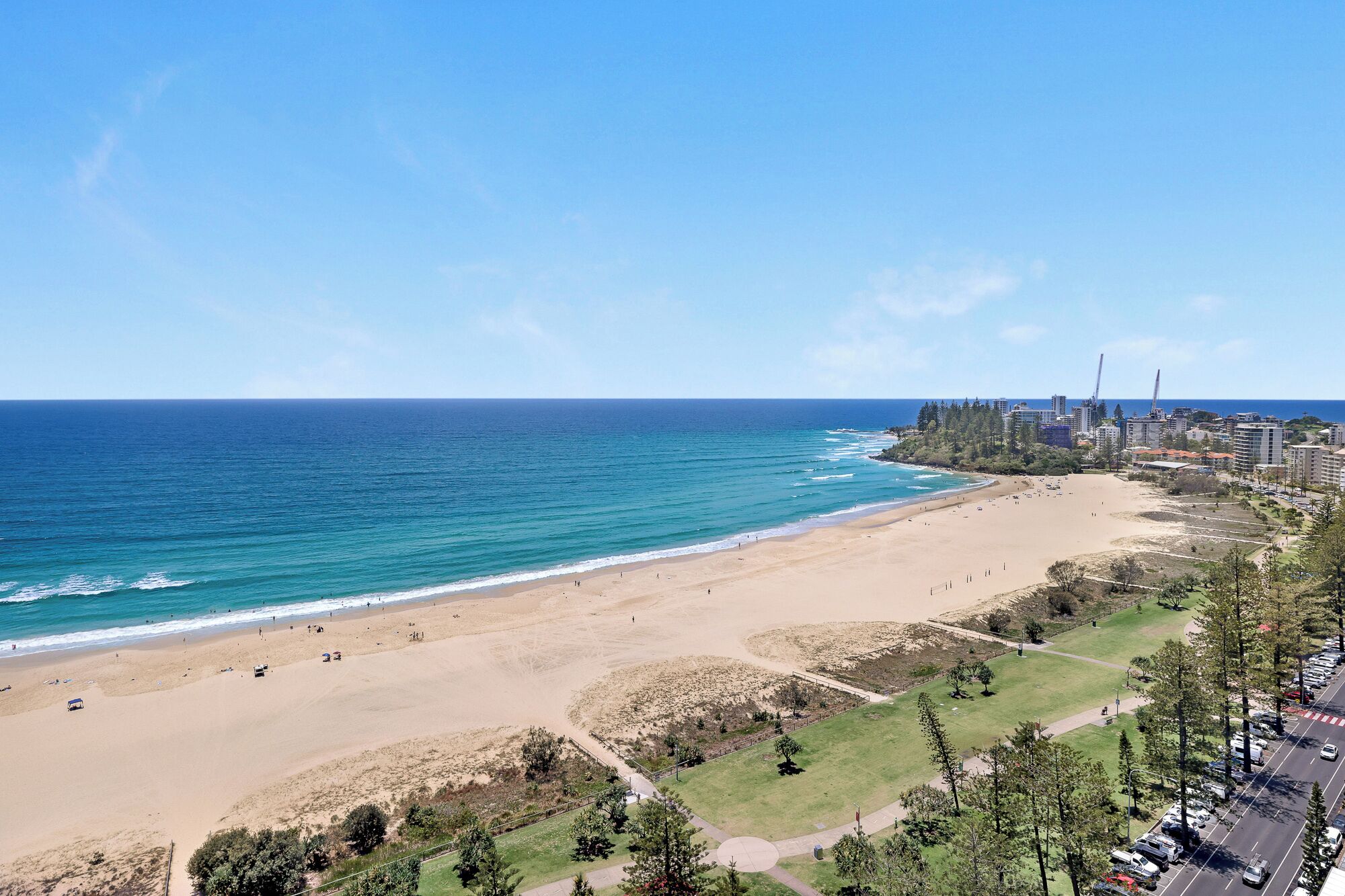 A beach with a clear view of the ocean and a cityscape in the background.