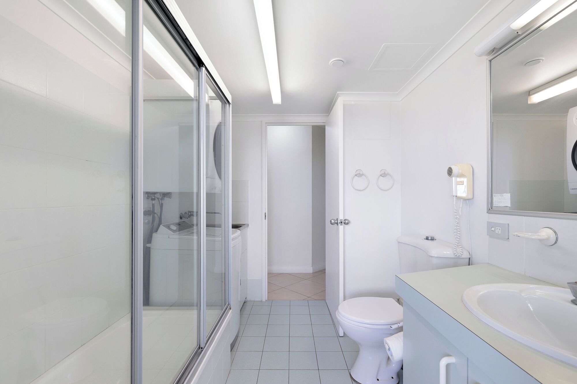 Un baño moderno con cabina de ducha de vidrio, un inodoro y un lavabo con espejo.